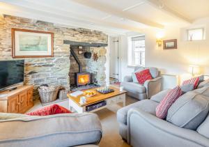 a living room with two couches and a stone fireplace at Popigale Cottage in Helford