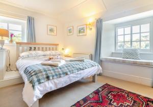 a bedroom with a bed and two windows and a rug at Popigale Cottage in Helford
