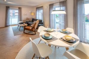 un salon avec une table et des chaises blanches dans l'établissement Ahoi, à Dornumersiel