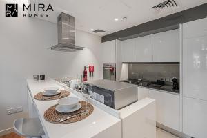 a white kitchen with a counter with dishes on it at Mira Holiday Homes - Serviced 1 bedroom in Bluewaters in Dubai