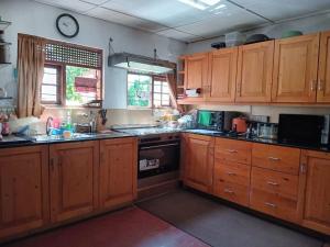 eine Küche mit Holzschränken und einer Uhr an der Wand in der Unterkunft SHADEY COTTAGE in Gampola