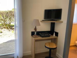 Habitación con mesa, TV y taburete. en Hotel Aux Tamaris, en Sauzon