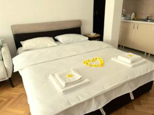 a bed with two white towels and yellow flowers on it at Center Apartment in Višegrad