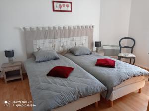 um quarto com uma cama grande e 2 almofadas vermelhas em Les 26 Tanneurs appartement em Noyon
