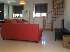 un sofá rojo en una sala de estar con una escalera en Figueira Praia Buarcos, en Figueira da Foz