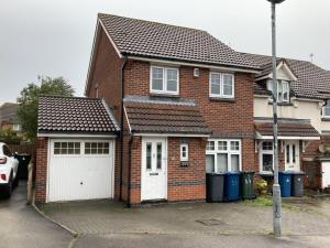 a brick house with two white garage doors at Quiet 3 bed semi with off street parking in Bingham