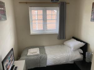 a small bedroom with a bed with a window at Quiet 3 bed semi with off street parking in Bingham