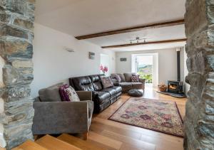 a living room with leather furniture and a stone wall at Bryn Eithin in Derwen