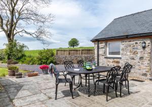 a patio with a table and chairs in front of a stone cottage at Bryn Eithin in Derwen