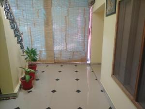 un bagno con pavimento piastrellato, finestra e 2 piante di Red king home stay a Bikaner