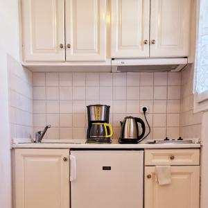 een keuken met witte kasten en een blender op de toonbank bij Panorama Apartments Fiscardo in Fiskardho