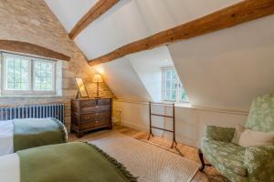 een slaapkamer op zolder met een bed en een stoel bij Coach House, Cold Aston in Bourton on the Water