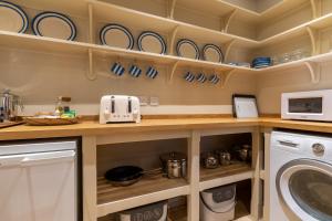 eine Küche mit einer Waschmaschine und einer Mikrowelle in der Unterkunft Coach House, Cold Aston in Bourton on the Water