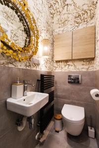 een badkamer met een wastafel, een toilet en een spiegel bij Wawel Castle View - City Center Suite in Krakau