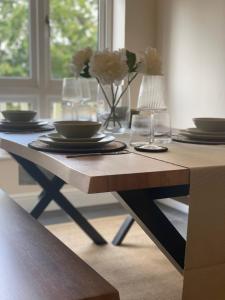 a table with plates and glasses and a vase with flowers at 2 Cherry Tree Cottages in Stock