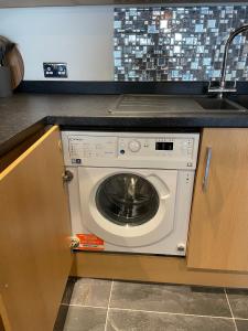 a washing machine in a kitchen under a sink at 2 Cherry Tree Cottages in Stock