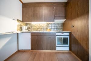 - une cuisine avec des placards en bois et un lave-vaisselle blanc dans l'établissement 3304 Preislich attraktives Studio im alpinen Stil, à Vulpera