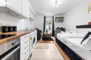 a kitchen and a bedroom with a bed and a sink at Modern Studio in Central Brixton, Stylish, Fast Wi-Fi & Parking in London +3 photos