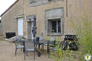 a table and chairs and an umbrella in front of a building at Gîte des teppes in Alixan