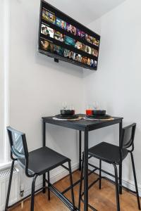 a black table with two chairs and a tv on the wall at Modern Studio in Central Brixton, Stylish, Fast Wi-Fi & Parking in London