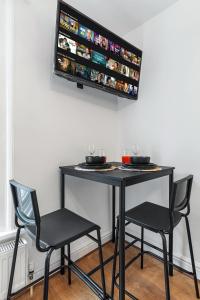 a black table with two chairs and a tv on the wall at Charis City Abode in London