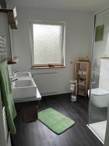 a bathroom with a sink and a tub and a window at Ferienwohnung "Wallheckenblick Schatteburg", 95159 in Rhauderfehn