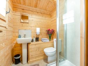 a bathroom with a toilet and a sink and a shower at Lochinvar - Clydesdale Log Cabin with Hot Tub in Airdrie