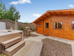 een houten huisje met een keuken en een patio bij Lochinvar - Clydesdale Log Cabin with Hot Tub in Airdrie