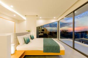 1 dormitorio con 1 cama grande y ventanas grandes en Yamu Hills Panoramic Ocean View 6 Bed Luxury Pool Villa - Phuket, en Phuket