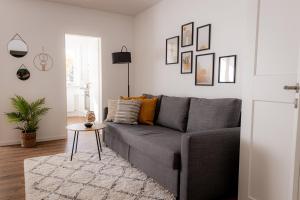 Come4Stay Passau - Apartment Seidenhof I voll ausgestattete Küche I Balkon I Badezimmer في باساو: غرفة معيشة مع أريكة رمادية وطاولة