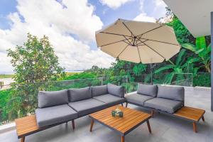 un patio con 2 sofás, una mesa y una sombrilla en Yamu Hills Panoramic Ocean View 6 Bed Luxury Pool Villa - Phuket, en Phuket