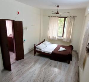 a small bedroom with a bed and a window at Haritha Apartments in Tirupati