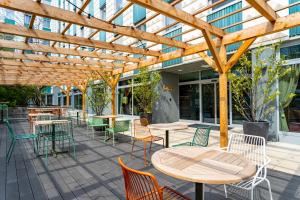 a patio with tables and chairs and a wooden pergola at The Weekend Hotel in Vienna