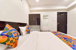 a bedroom with a white bed with colorful pillows at FabHotel Shri Krishna in Vadodara