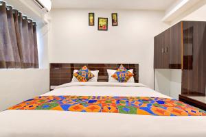 a bedroom with a king sized bed with a colorful quilt at FabHotel Shri Krishna in Vadodara