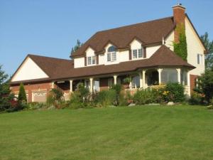 a large house with a large lawn in front of it at Clearview Station & Caboose B&B in Creemore