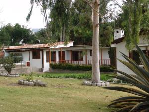 una casa blanca con un árbol en el patio en La Posada Del Aromito - Apartment, en Cumbayá