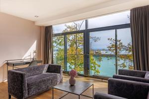 ein Wohnzimmer mit großen Fenstern und Blick auf das Wasser in der Unterkunft aika seaside living hotel in Friedrichshafen