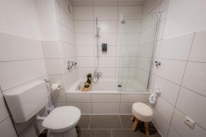 a white bathroom with a toilet and a bath tub at Come4Stay Passau - Apartment Seidenhof I voll ausgestattete Küche I Balkon I Badezimmer in Passau +47 photos