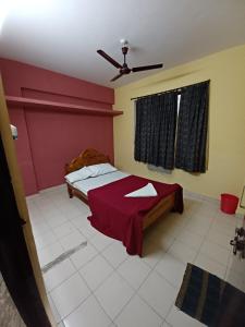 a bedroom with a bed with a red wall at Haritha Apartments in Tirupati
