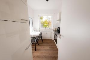 eine Küche mit einem Kühlschrank, einem Tisch und einem Fenster in der Unterkunft Come4Stay Passau - Apartment Seidenhof I voll ausgestattete Küche I Balkon I Badezimmer in Passau