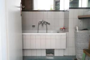 a white tiled bathroom with a sink at Family apartment in the city centre - FREE parking garage in Ljubljana