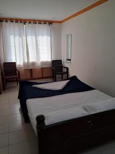 a bedroom with a large bed and two chairs at Haritha Apartments in Tirupati