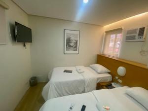 a small room with two beds and a tv at Aurora Suites in Manila