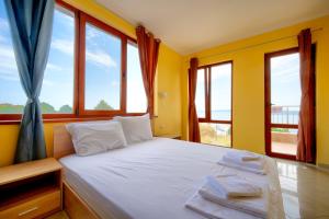 a bedroom with a white bed with windows at Stefaniya Apartments in Sozopol