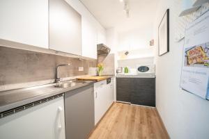 uma pequena cozinha com armários brancos e um lavatório em 4103 Charmantes, neu renoviertes Studio em Vulpera