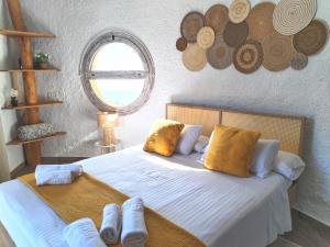um quarto com uma cama com lençóis brancos e almofadas amarelas em Hotel Rural los Caracoles em Frigiliana