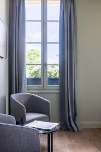 sala de estar con silla y ventana en Hotel Porte Brunet en Saint-Émilion