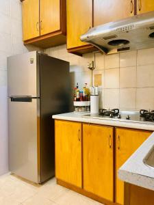 een keuken met een roestvrijstalen koelkast en houten kasten bij D MARINE’ HOMESTAY in Kota Kinabalu
