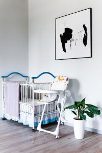 a baby crib in a white room with a plant at Gardens Residence in Tashkent